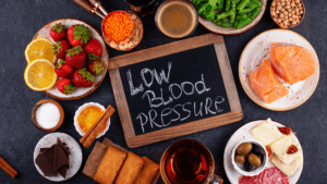 A picture of small chalk board with he words :Low blood pressure" on it. The board is surroundedby various plates of food