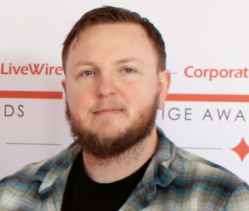 A man with his arms folded, wearing a beard and a hat.